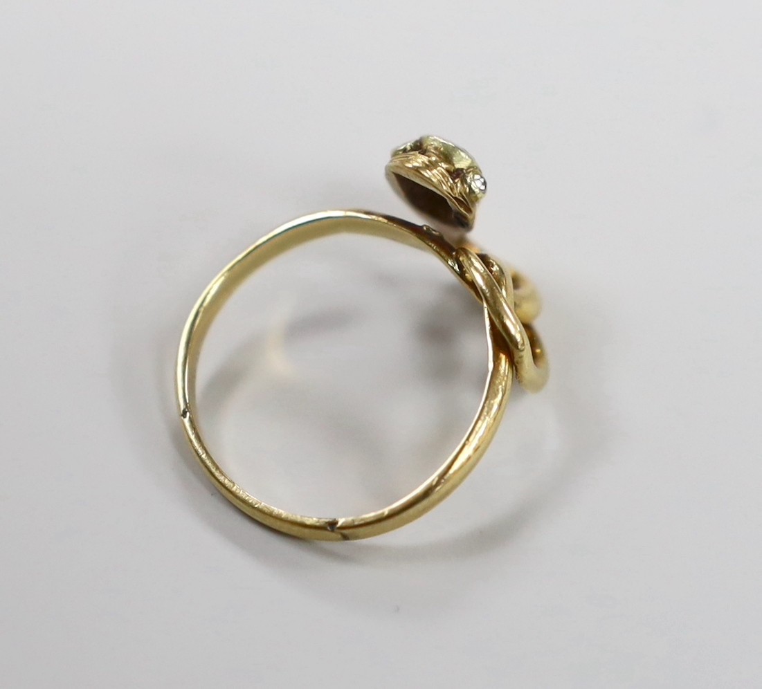 An early 20th century yellow metal and single stone garnet set entwined serpent ring, with diamond chip eyes, size O, gross weight 3.7 grams.